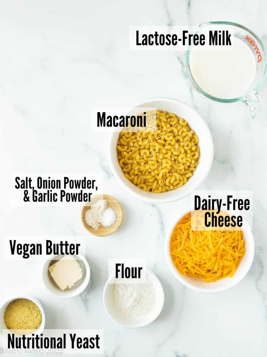 ingredients for making lactose free mac and cheese measured out into bowls on a white table.