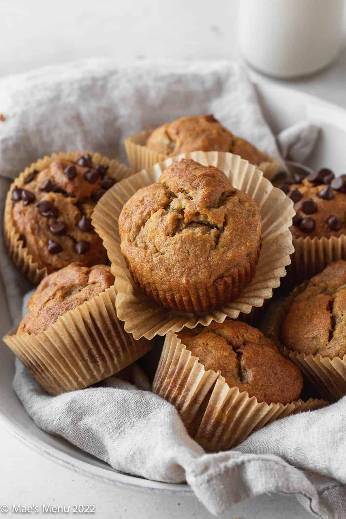 white serving bowl filled with half dairy-free banana muffins and half dairy-free banana chocolate chip muffins.