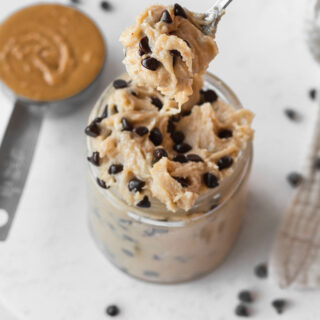 A spoonful of the edible cookie dough and a small cup of the cookie dough.