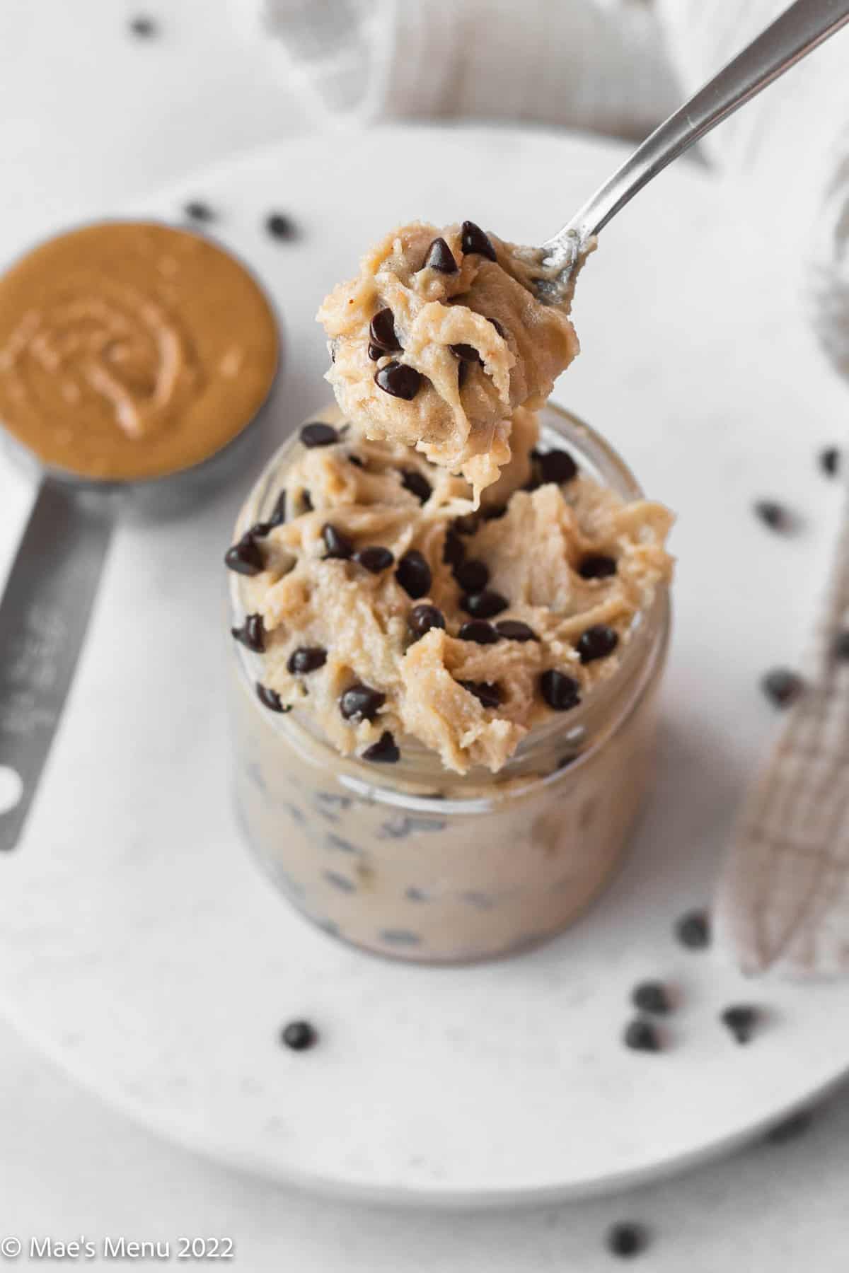 A spoonful of the edible cookie dough and a small cup of the cookie dough.