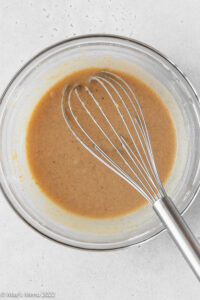 A glass mixing bowl of creamed peanut butter, sugar, and milk.