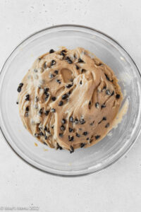 A glass mixing bowl of the peanut butter cookie dough with chocolate chips.