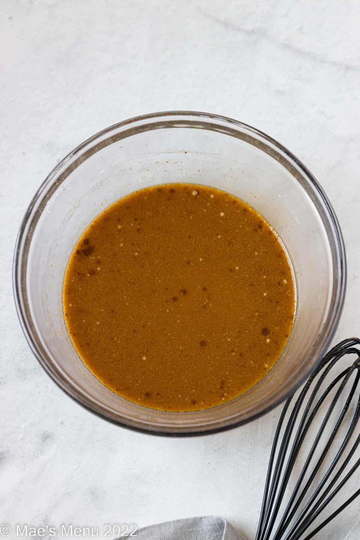 The orange stir fry sauce whisked up in a glass bowl.