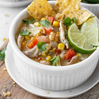 An up-close shot of a white bowl of creamy white chicken tortilla soup.