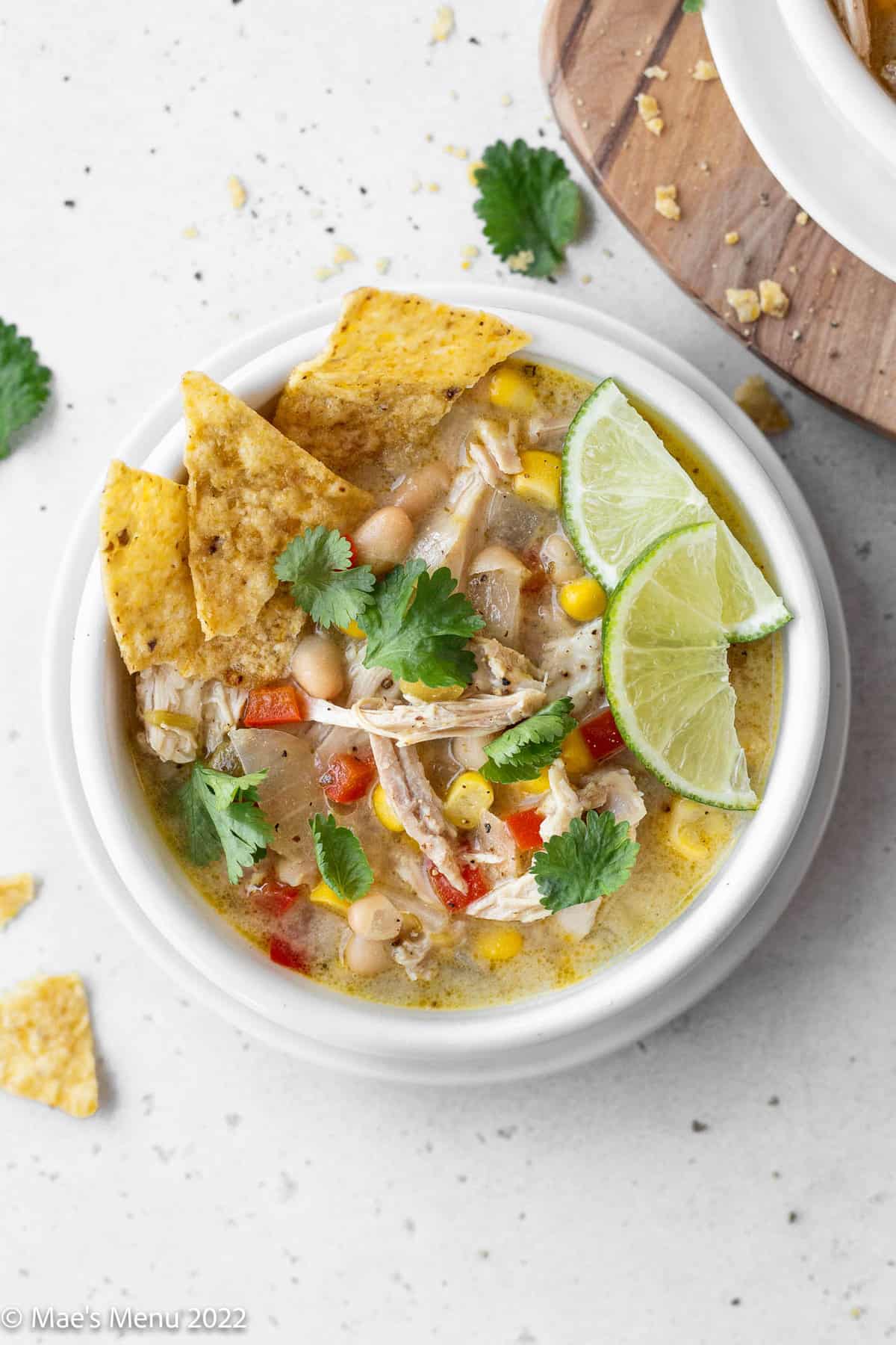 A white bowl of creamy white chicken tortilla soup on a white background.