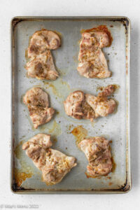 Baked chicken thighs on a baking sheet.