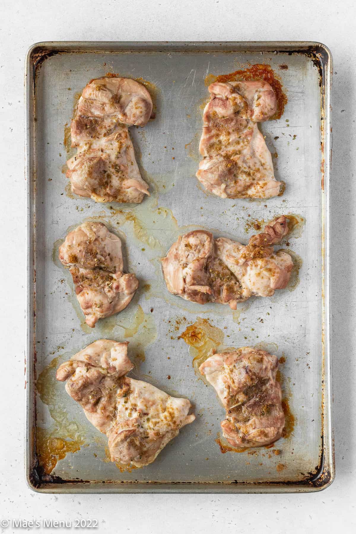 Baked chicken thighs on a baking sheet.