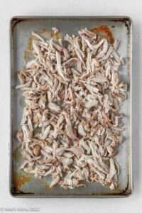 Shredded chicken thighs on a baking sheet.
