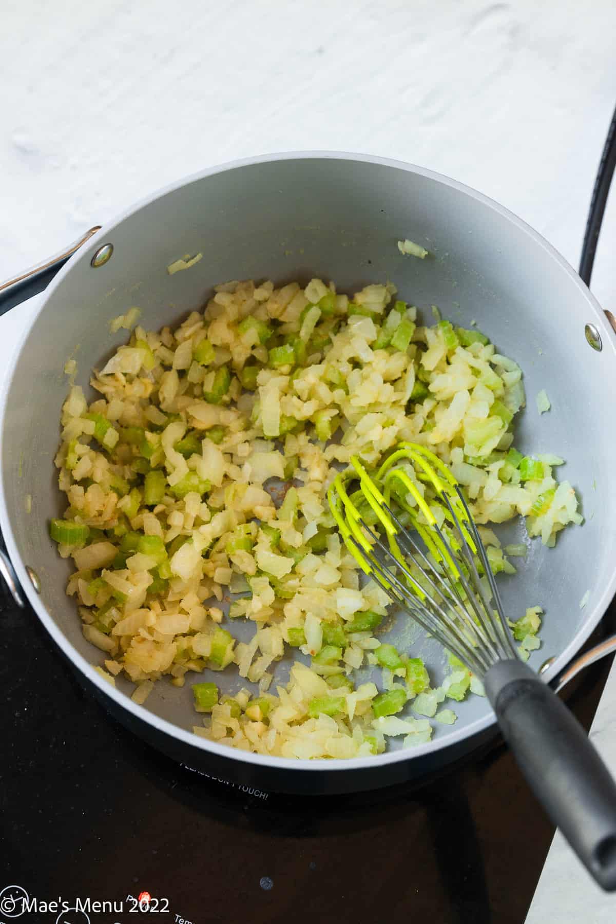 Whisking flour into a pan of onions and celery.