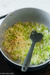 Adding garlic to a pan of celery and onions.