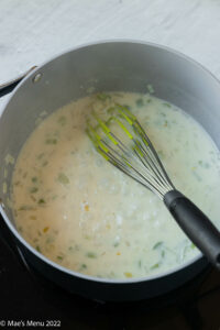 A large pan of milk simmering with onions and celery.