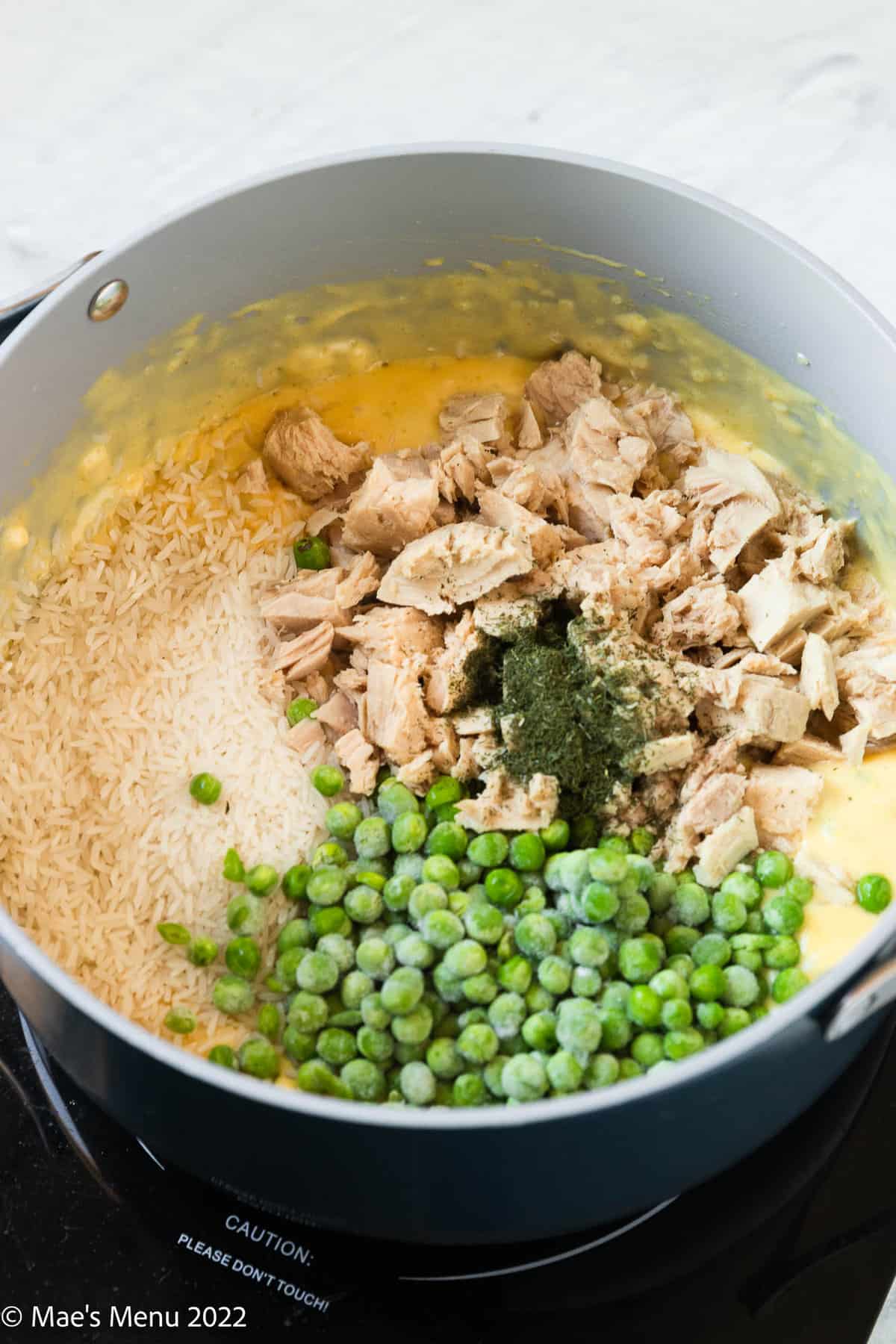 A large pot of rice, tuna, peas, and cheese sauce.