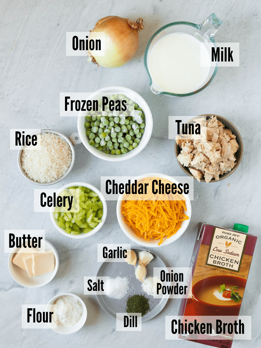 All of the ingredients for cheesy tuna rice casserole: onion, milk, frozen peas, tuna, rice, celery, cheddar cheese, butter, garlic, salt, onion powder, dill, flour, and chicken broth.