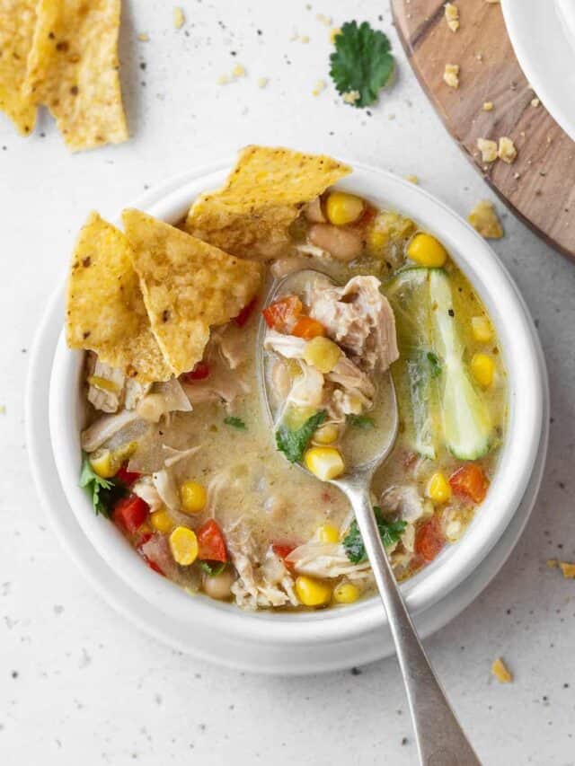A spoonful of white chicken tortilla soup in a bowl of the soup.