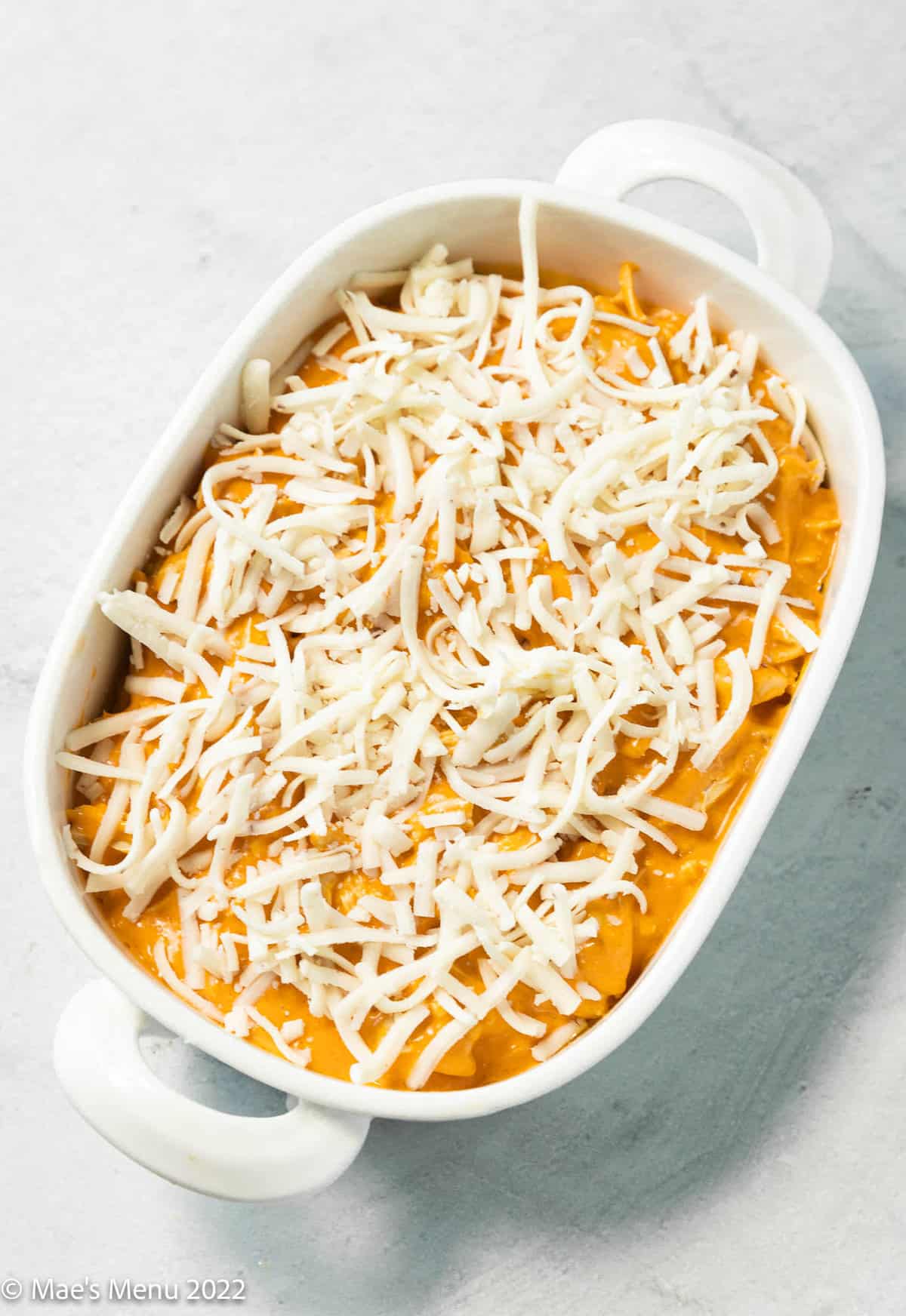 buffalo chicken dip transferred to a white baking dish and topped with vegan mozzarella shreds before baking.