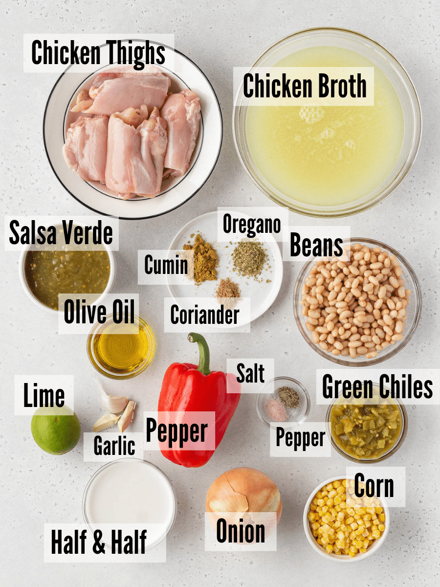 All of the ingredients for white chicken tortilla soup: chicken thighs, chicken broth, beans, spices, olive oil, salsa verde, beans, green chiles, salt, pepper, corn, onions sweet pepper, garlic, lime, and half & half.