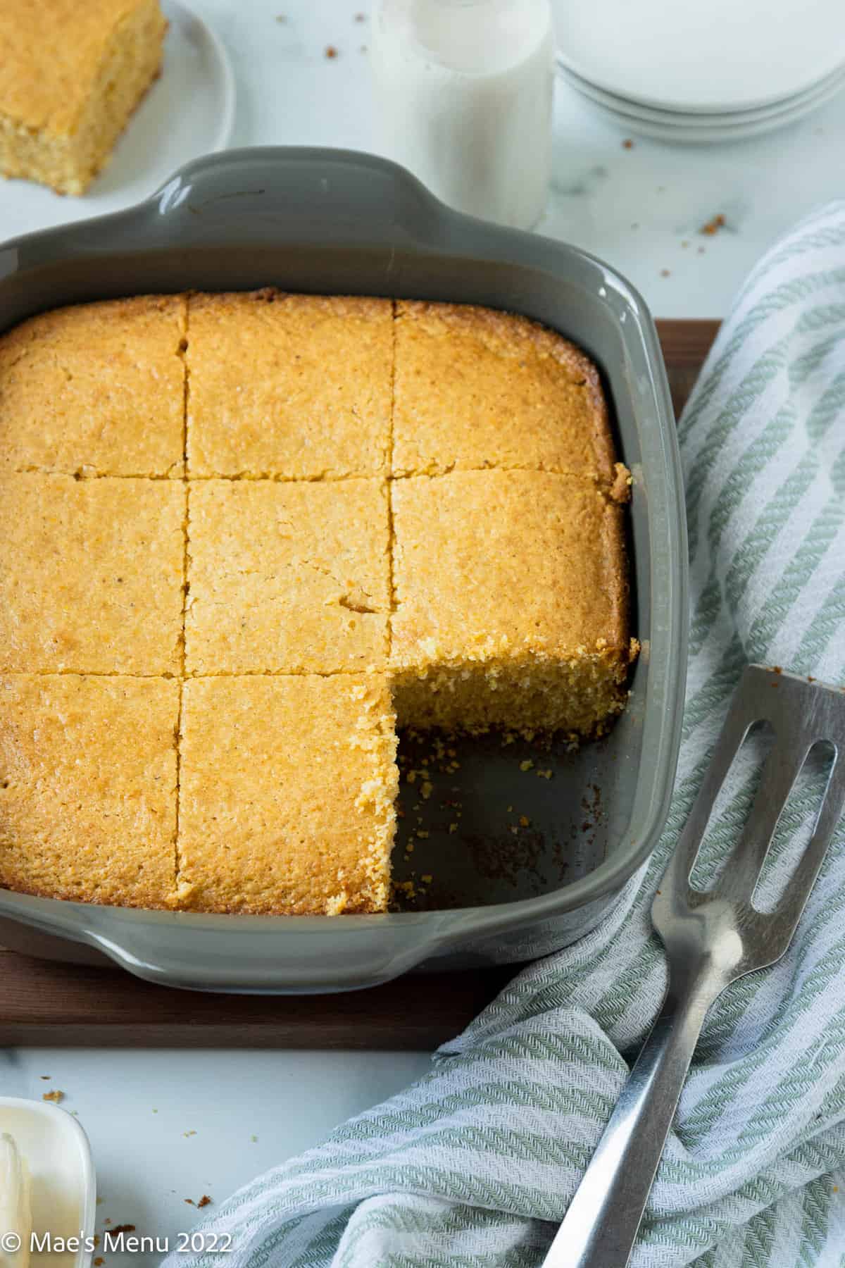 A grey pan of sliced dairy free cornbread with a slice taken out of it.