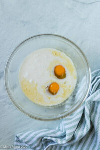 A glass bowl with melted butter, coconut milk, and eggs.