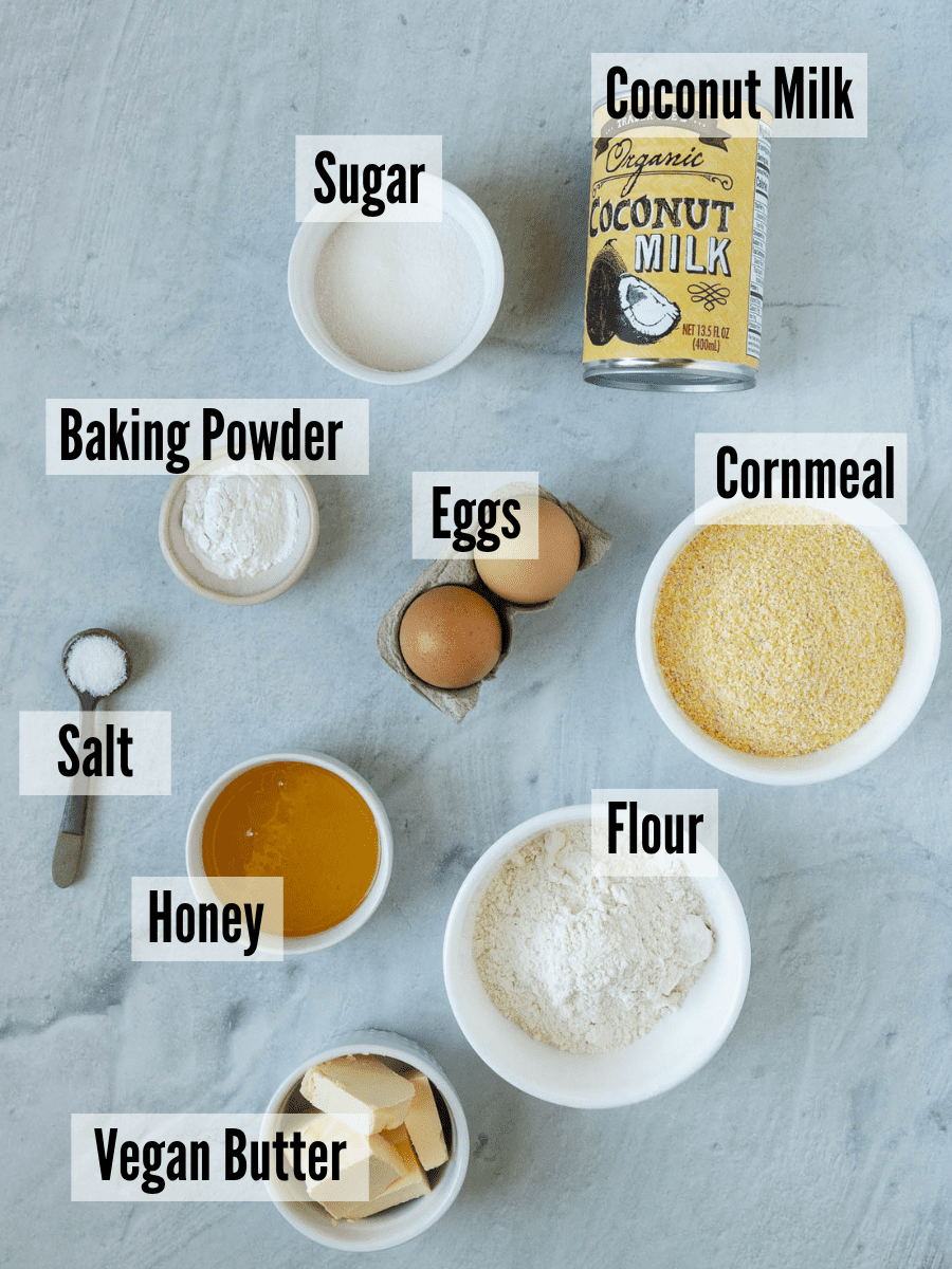 All of the ingredients for cornbread without milk: coconut milk, cornmeal, flour, eggs, baking powder, sugar, honey, vegan butter, and salt.