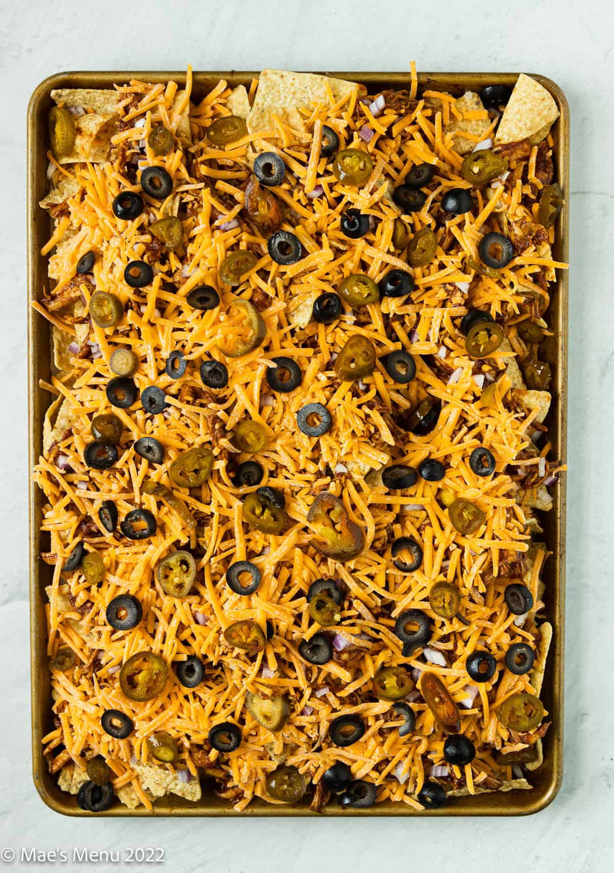 A baking sheet of loaded bbq chicken nachos before going in the oven.