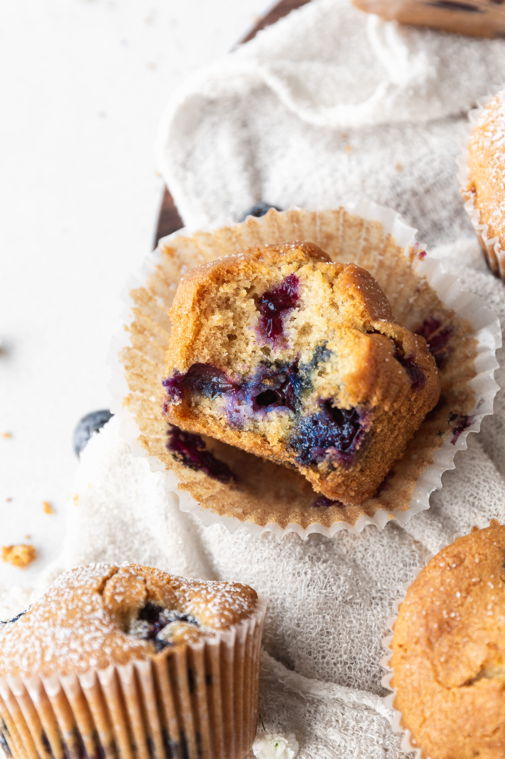 A side shot of a dairy-free blueberry muffin with a bit taken out of it.