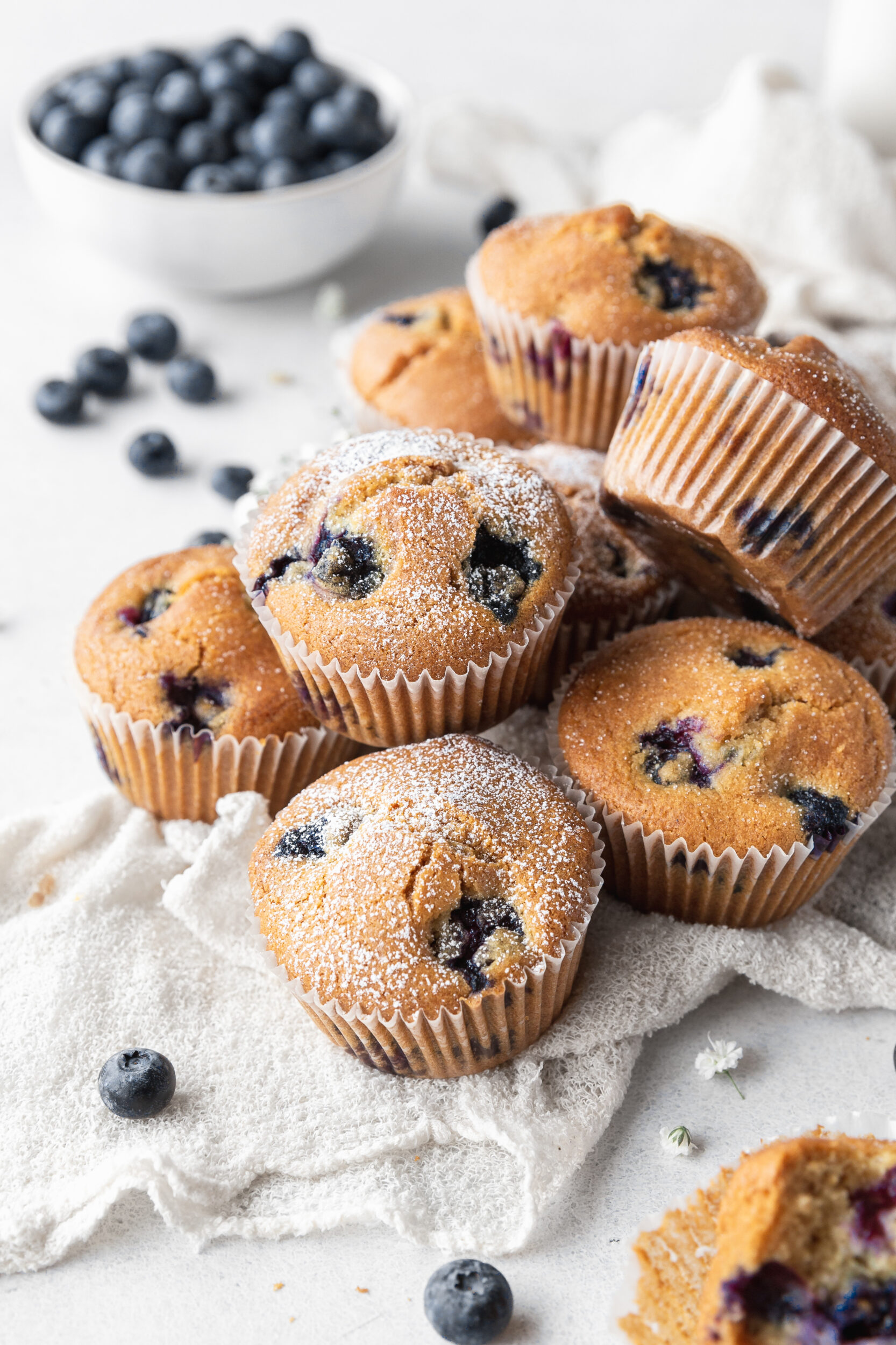 An up-close shot of dairy-free blueberry muffins piled on a cloth on the counter.