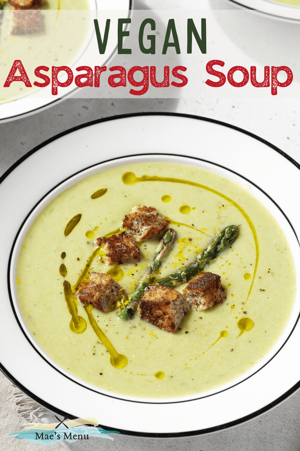 A pinterest pin for asparagus soup without cream with an up-close shot of a white bowl of the soup drizzled with olive olive, croutons, and asparagus.