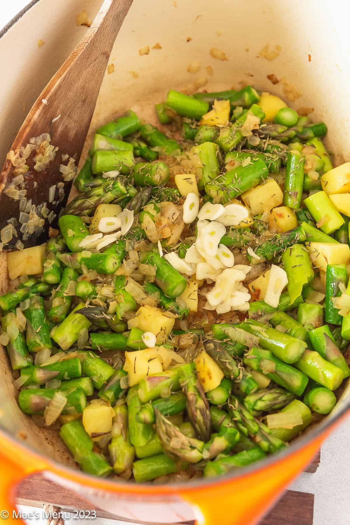 Sauteing the asparagus and potatoes in the pot with the garlic and other seasonings.