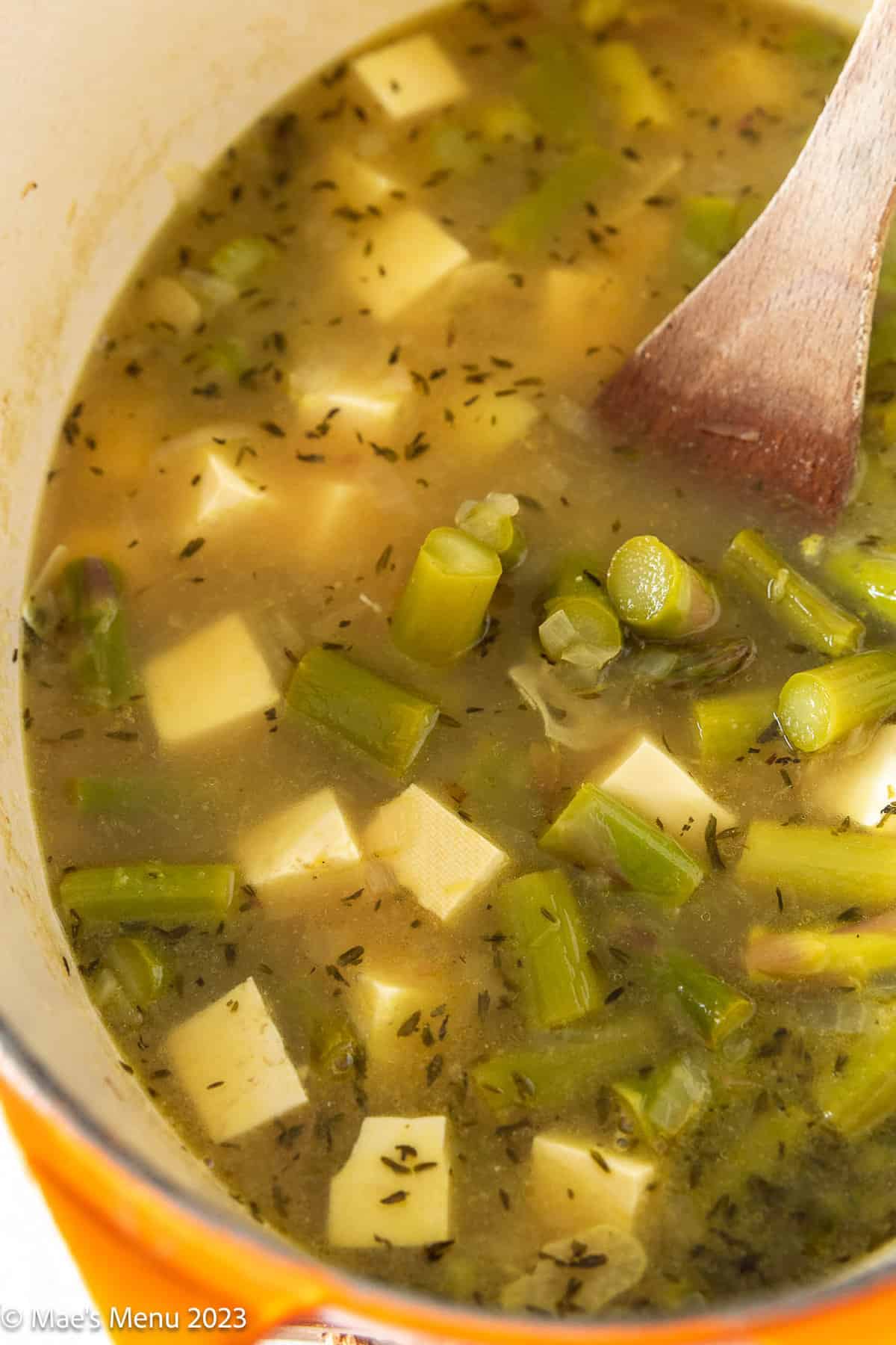 A large pot of simmered asparagus and tofu in the broth.