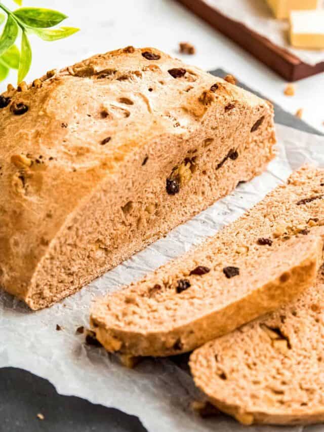 A sliced loaf of walnut bread on parchment paper.
