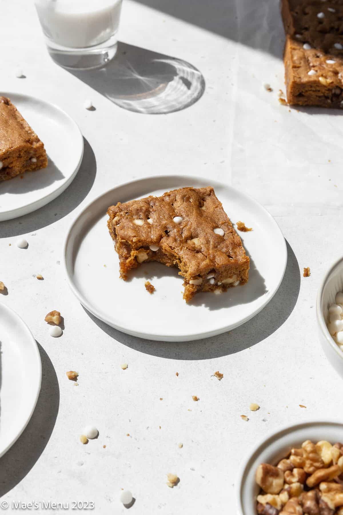 Vegan blondies on a small plate with a bite taken out of it.