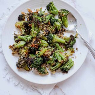 A white plate of frozen air fryer broccoli with a spoon.