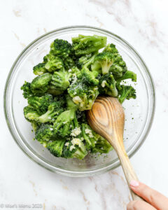 Stirring the frozen broccoli with a wooden spoon.
