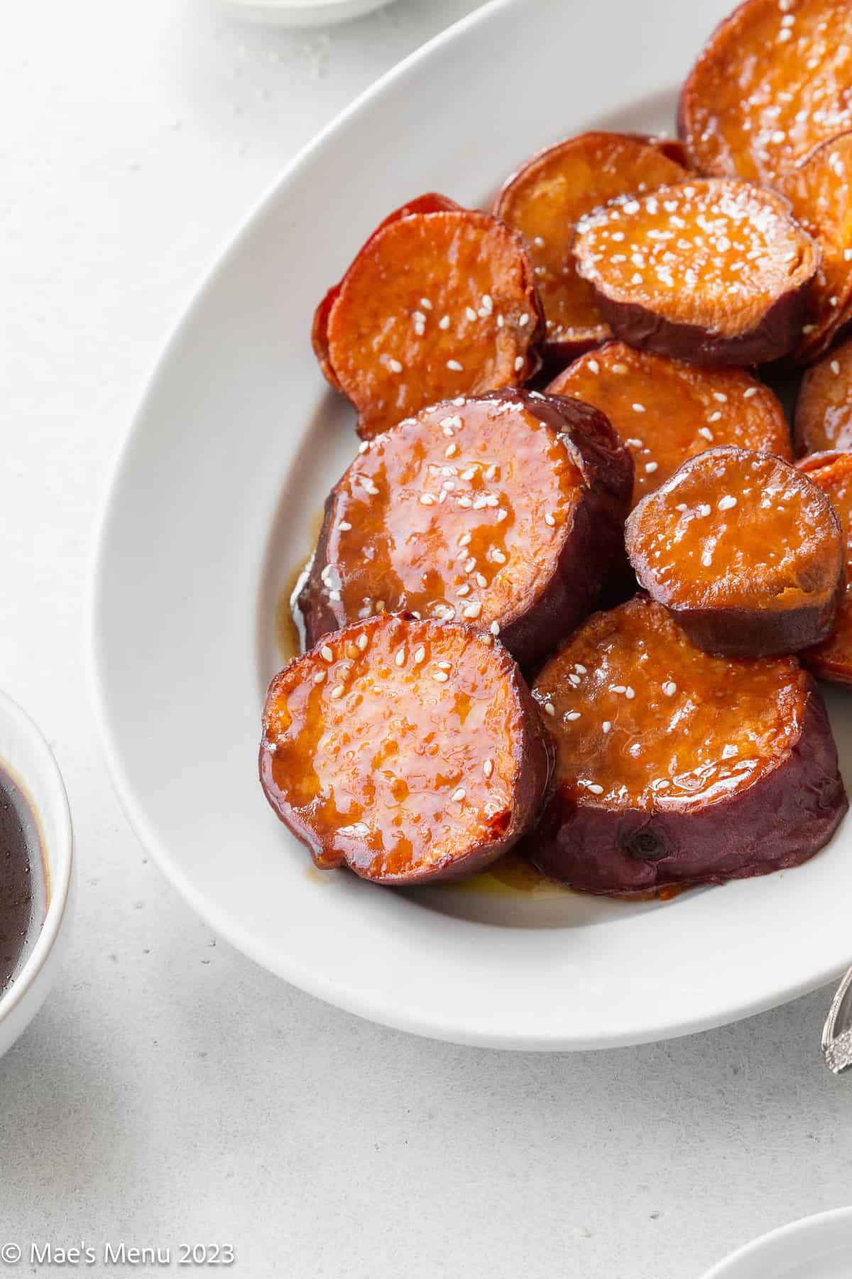 Crispy roasted sweet potatoes with miso maple glaze on a white serving plate.