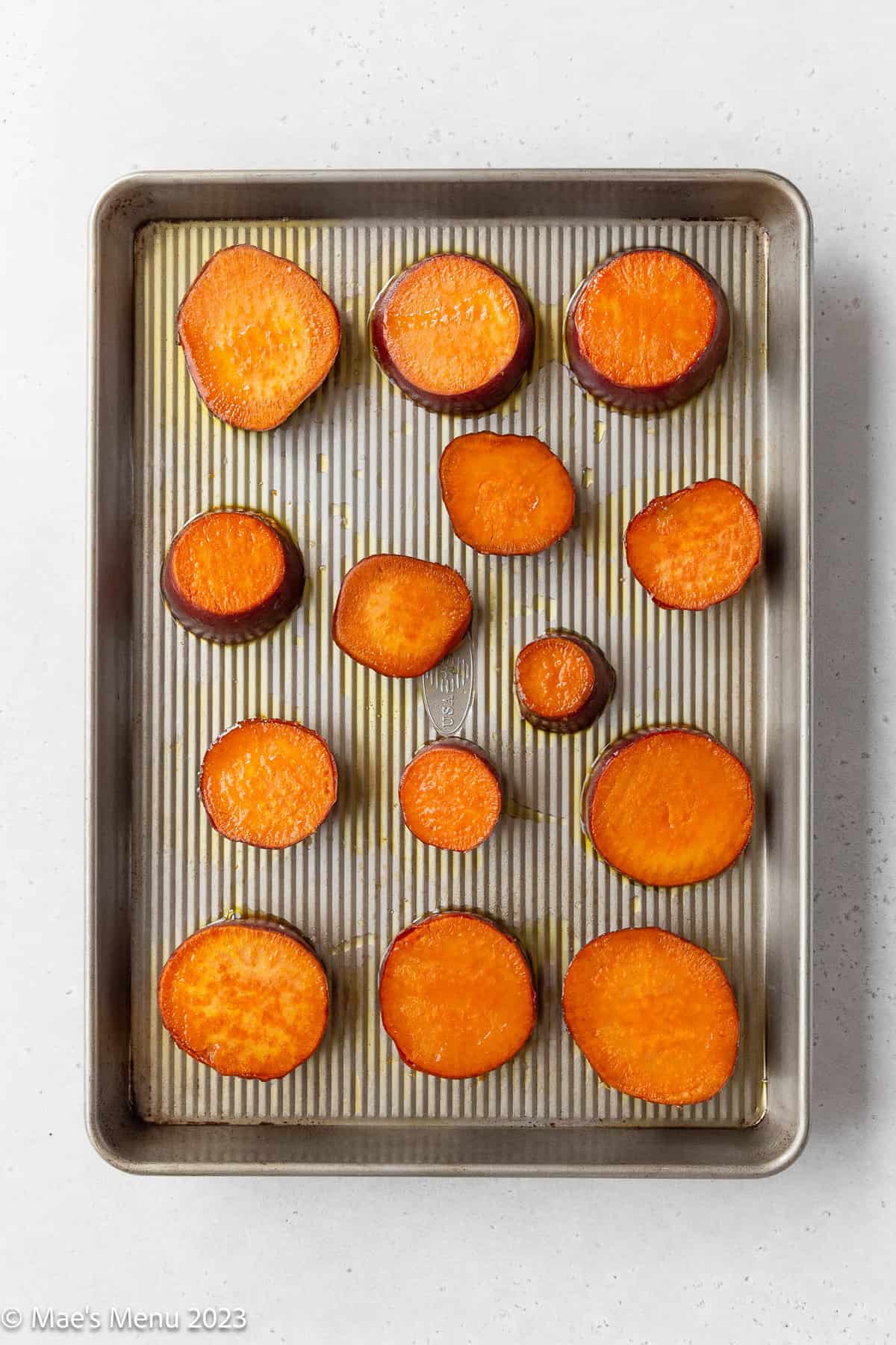 Sliced sweet potatoes brushed with olive oil on a large baking dish.