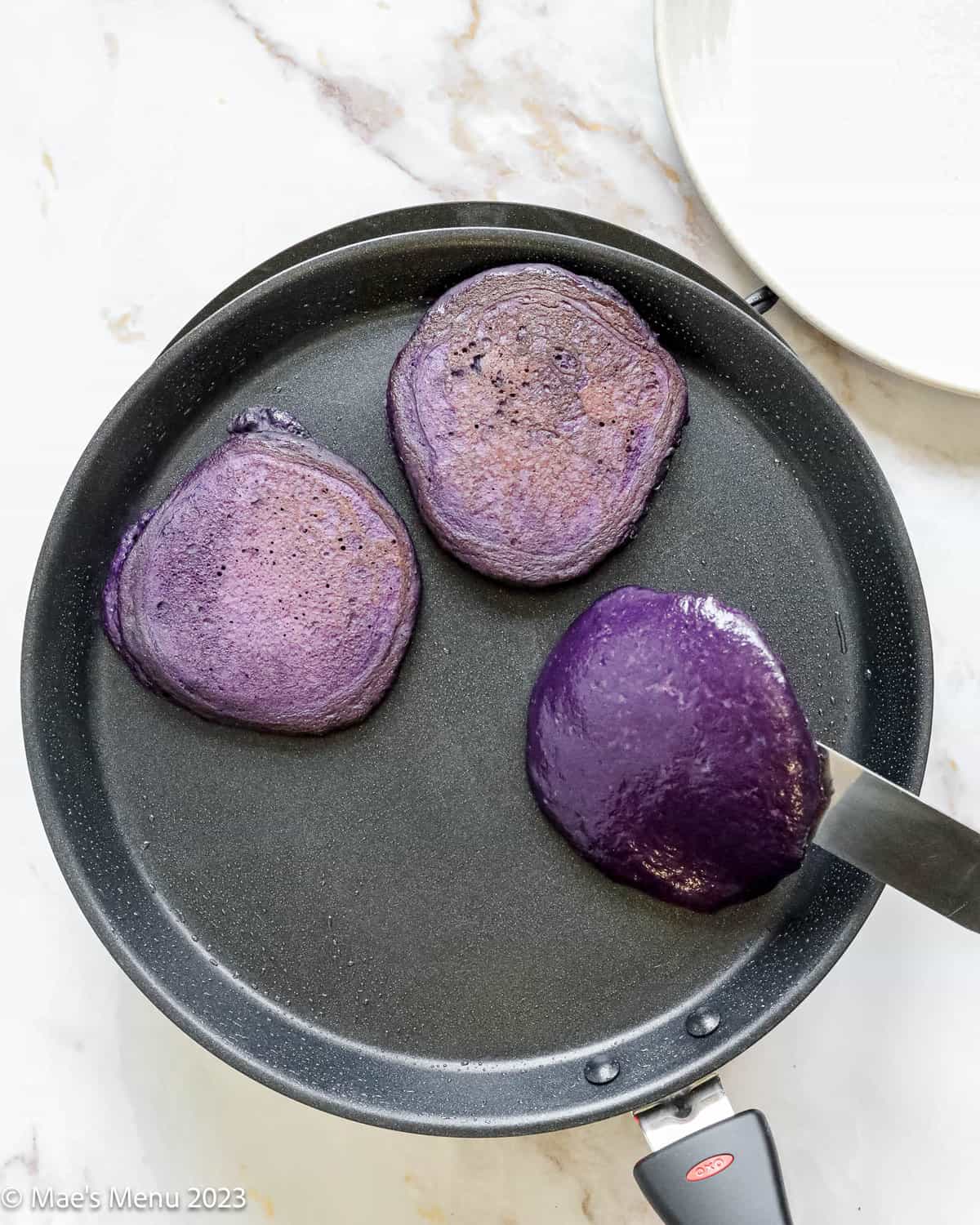 Turning the ube pancakes on a griddle.