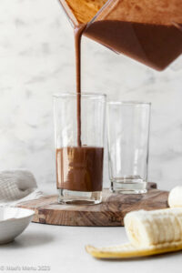 Pouring the chocolate banana protein smoothie into glasses.