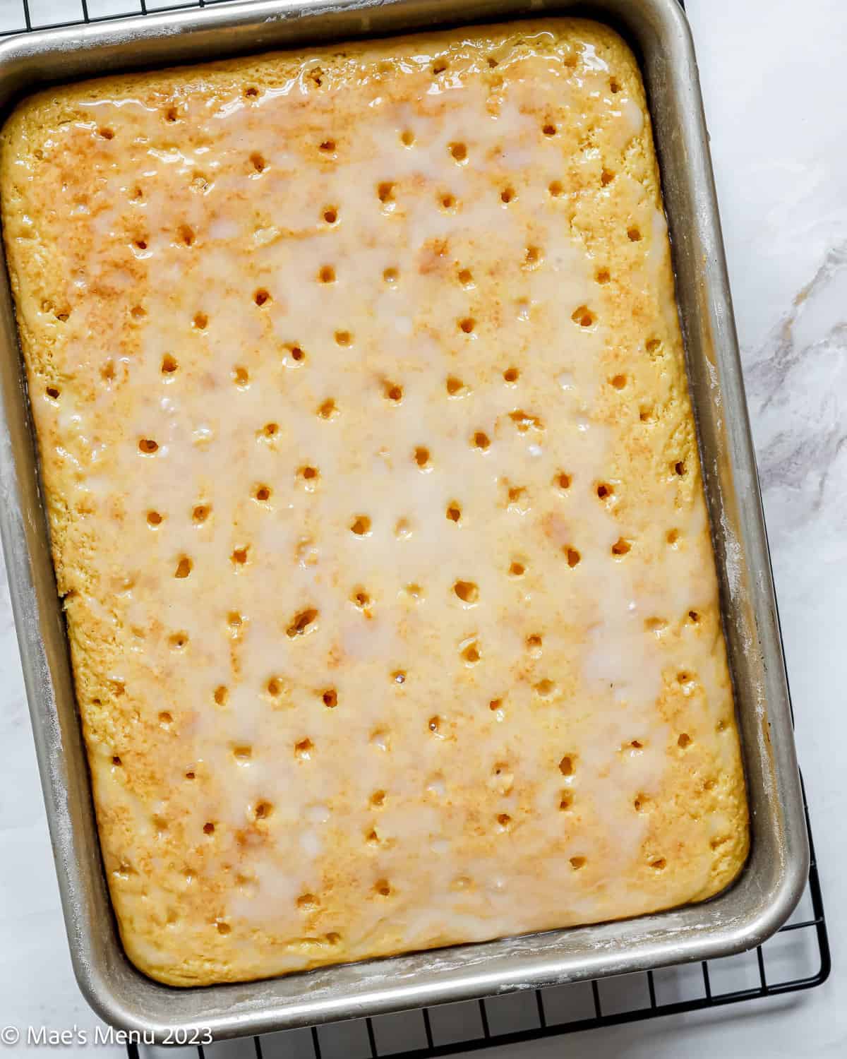 A hot pan of lemon poke cake with the lemon glaze on top.