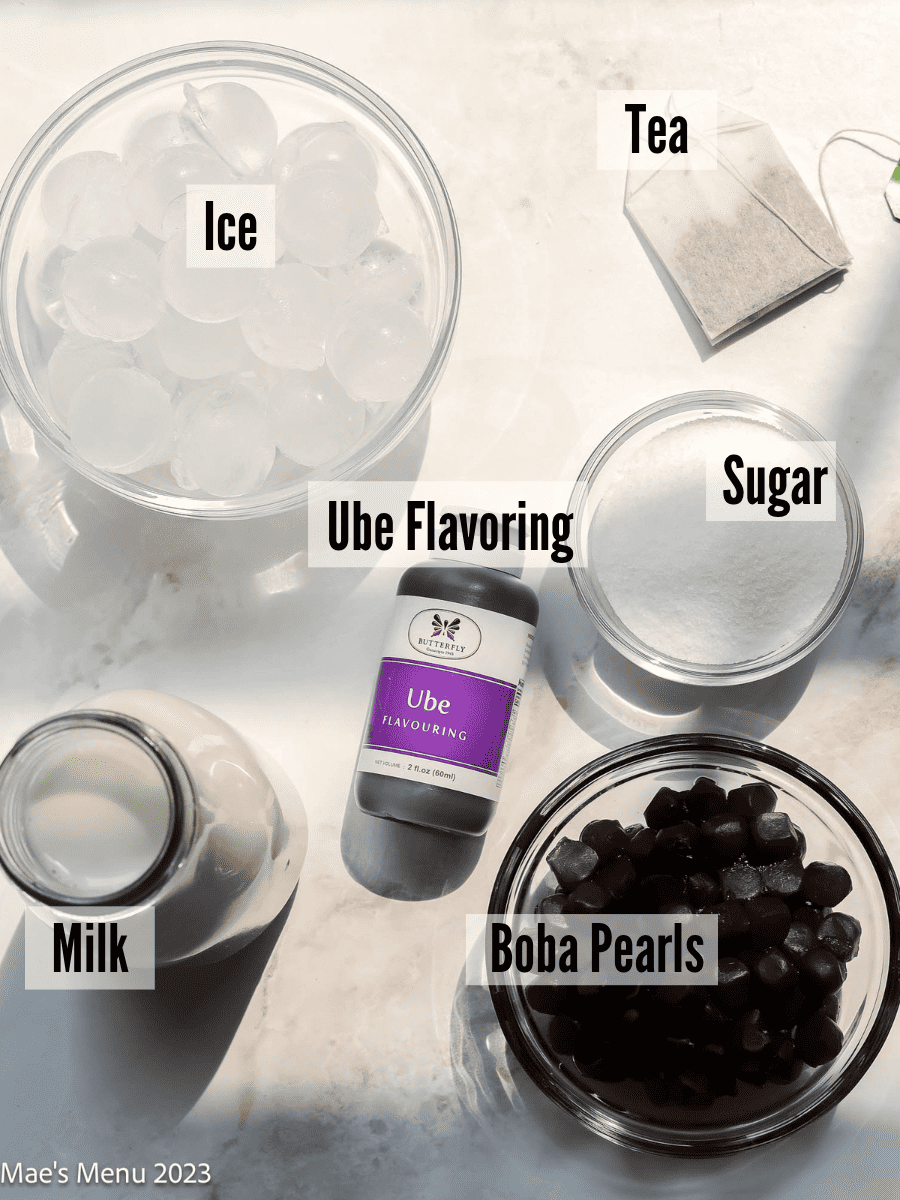 All of the ingredients for purple boba tea on a countertop.