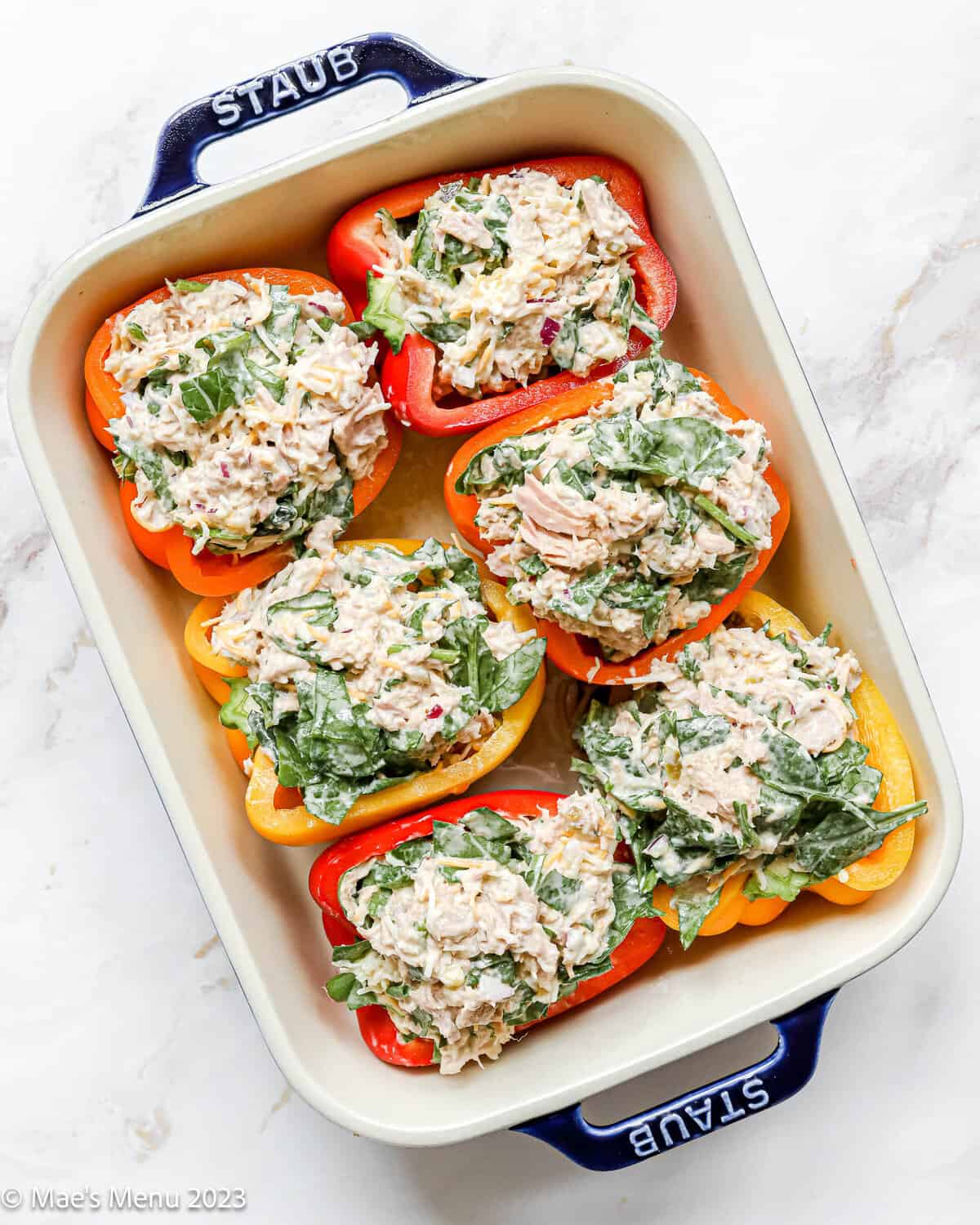 A large ceramic pan with tuna stuffed peppers before baking.