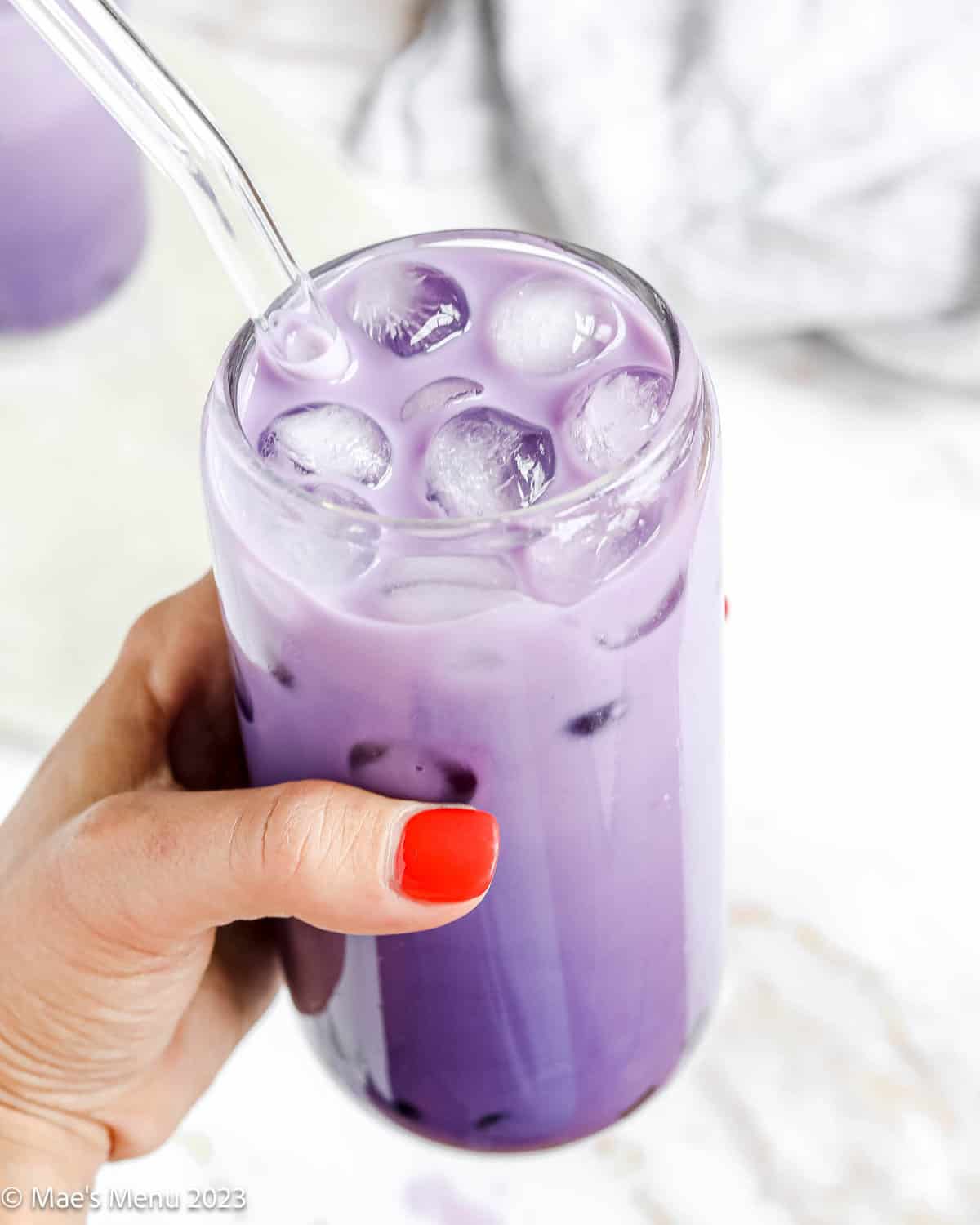 A shot of a hand holding a glass of ube boba.