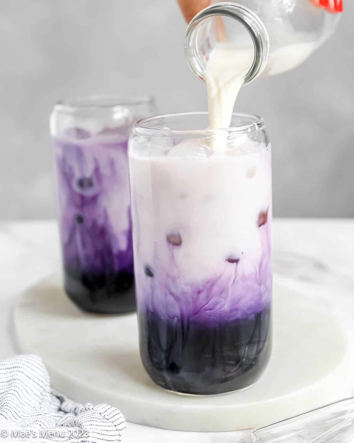 Pouring the milk in with the ube tea.