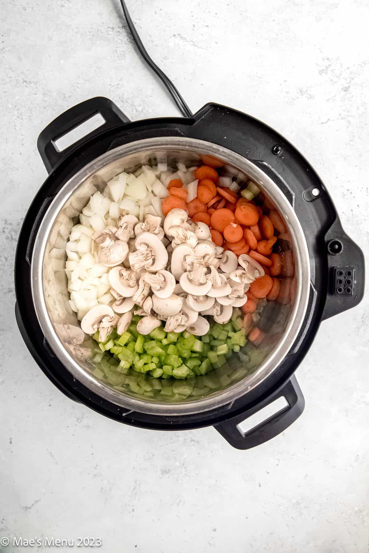 Onions, carrots, mushrooms, and celery in an Instant Pot.