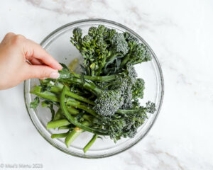 Seasoning the broccolini with salt.