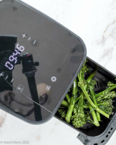 Adding the broccolini to the air fryer.