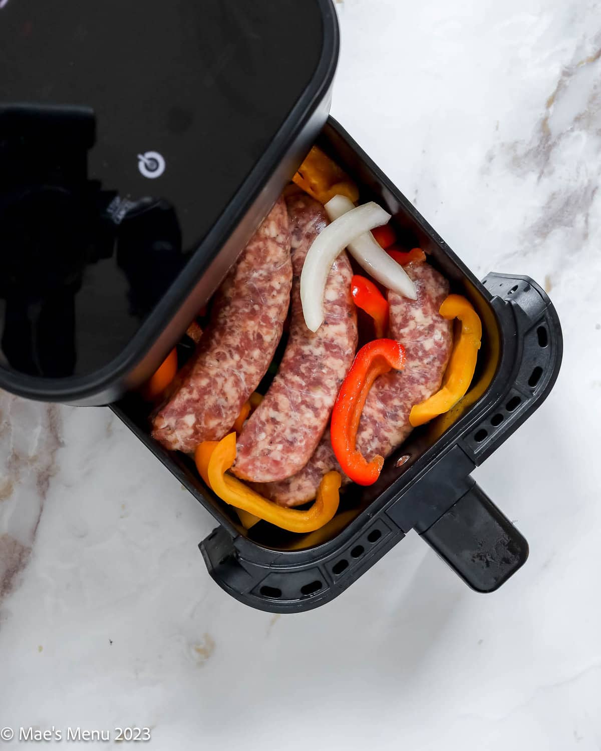 Italian sausage, peppers, and onions in the air fryer basket.