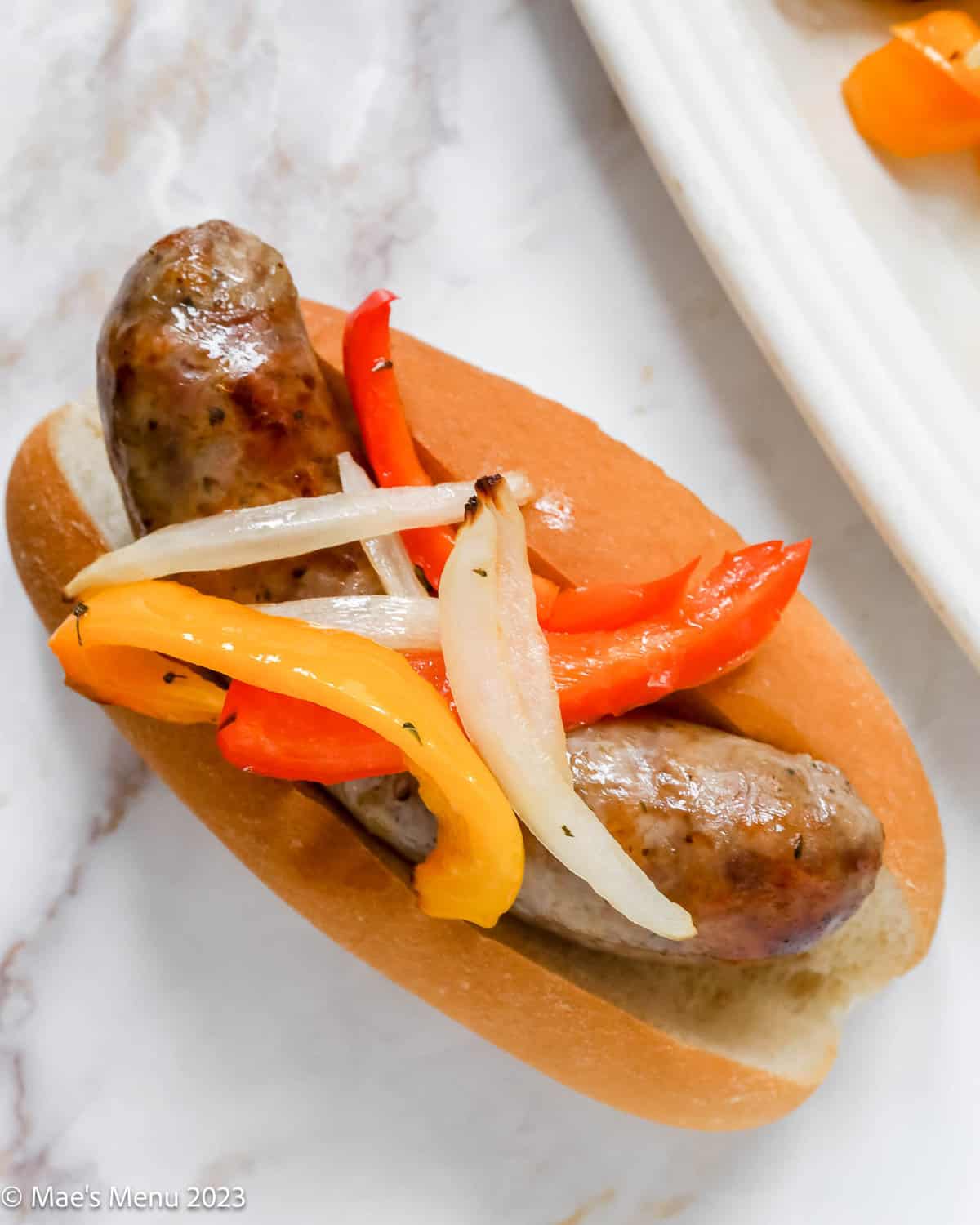 A closeup of air fryer Italian sausage and peppers in a bun.