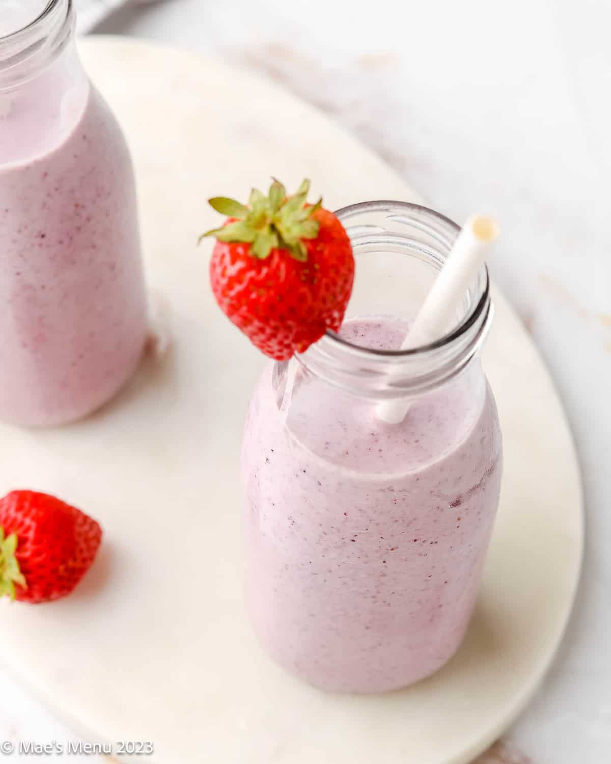 A close-up of a cottage cheese smoothie with a straw and a strawberry.