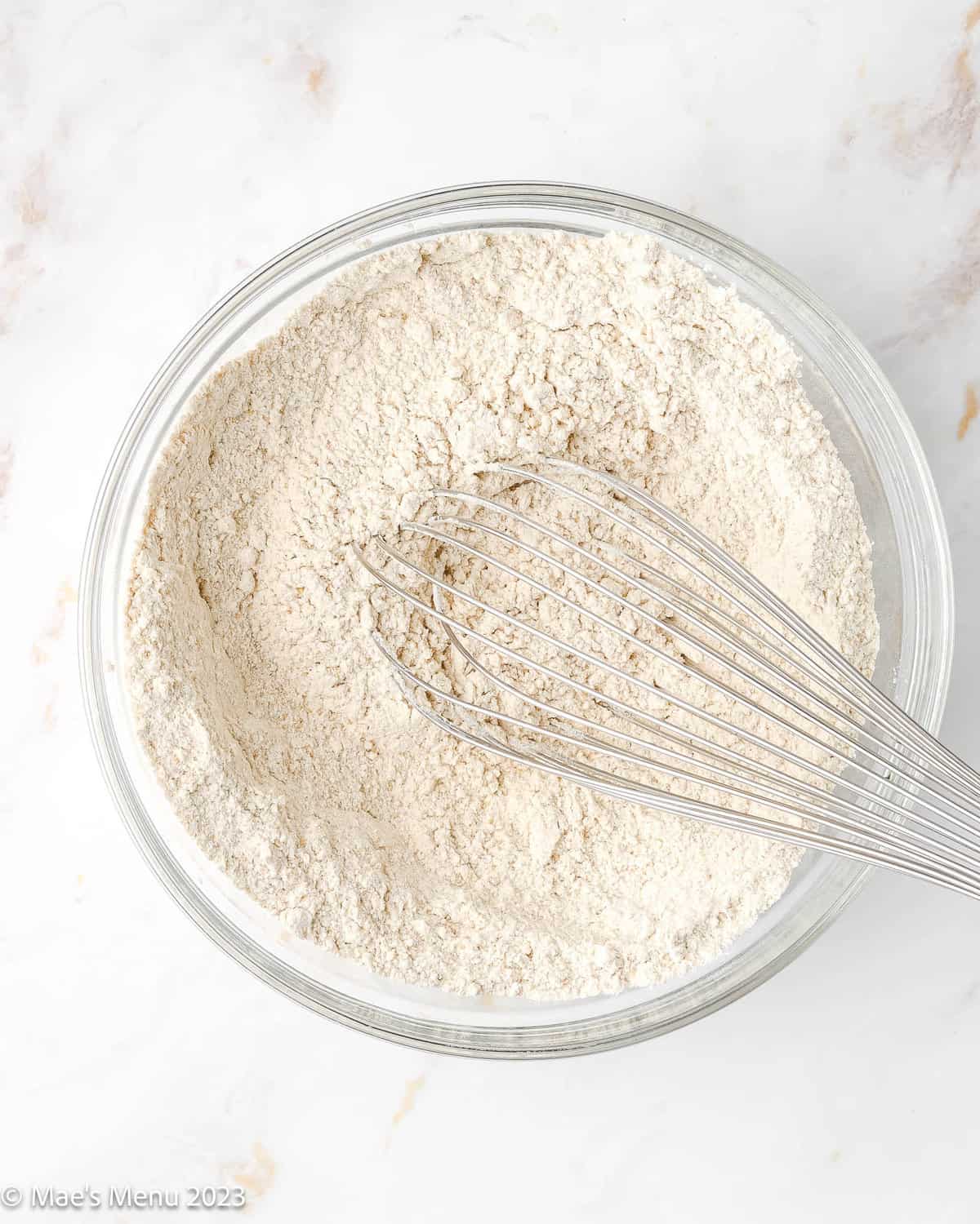 Whisking the flour and ingredients together in a glass mixing bowl.