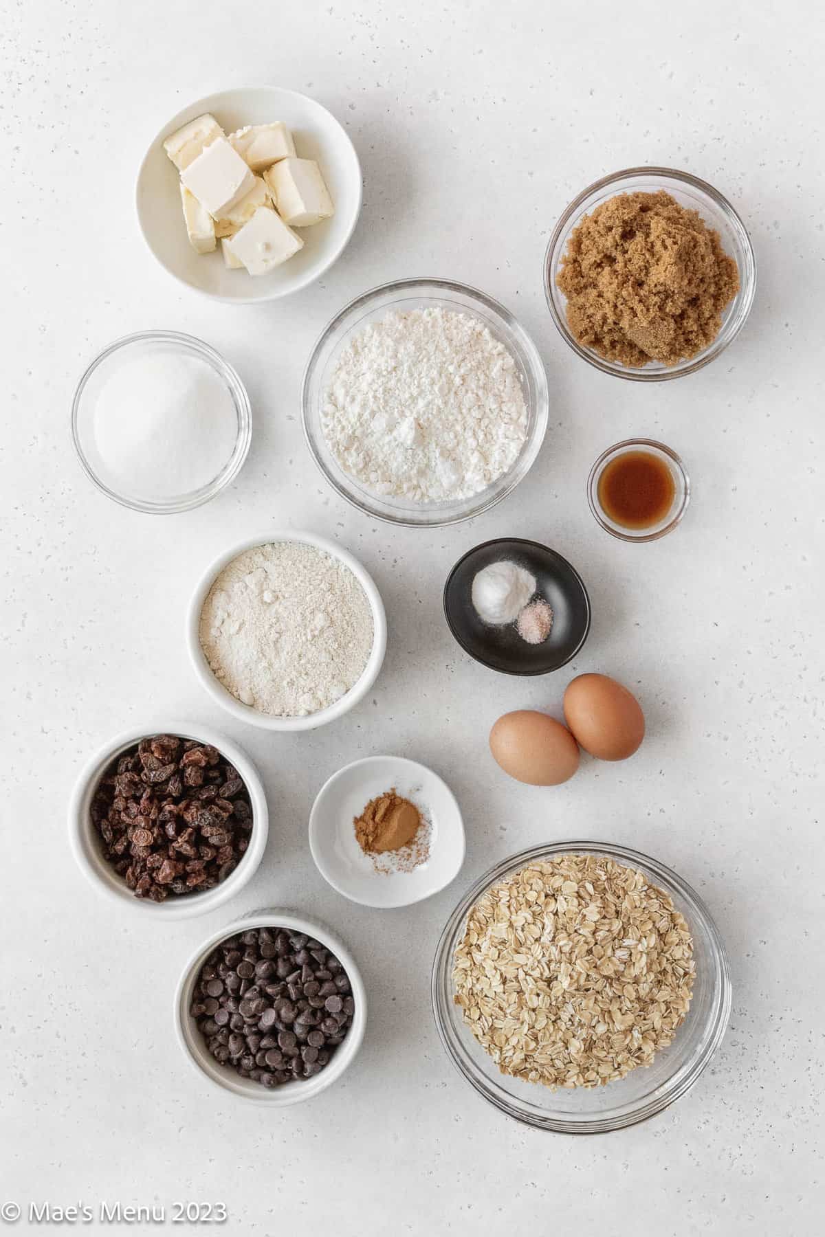 All of the ingredients for oatmeal raisin chocolate chip cookies on a white background.